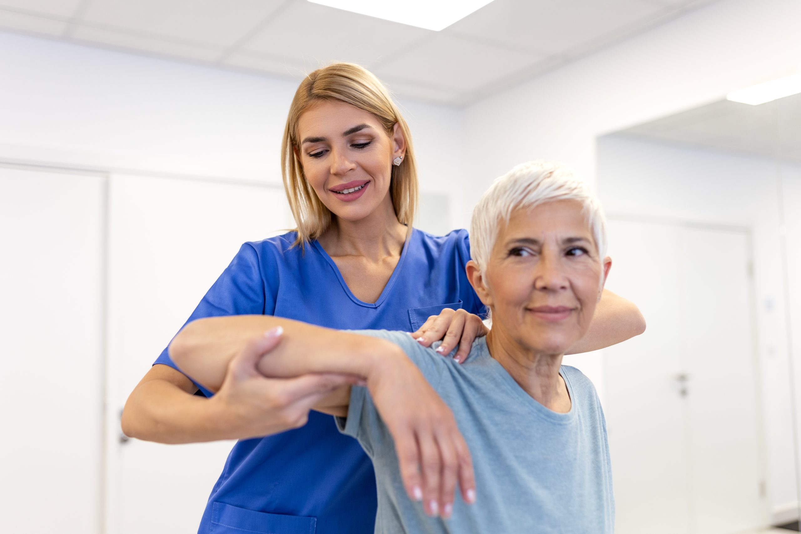 Doctor or Physiotherapist working examining treating injured arm of senior female patient, stretching and exercise, Doing the Rehabilitation therapy pain in clinic.